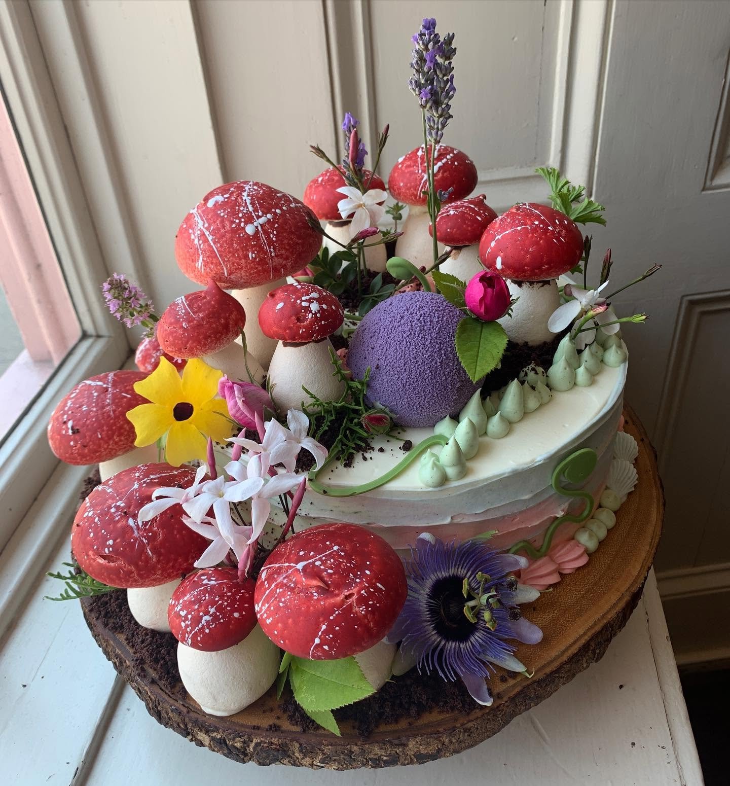 An intricate cake decorated with meringue mushrooms and edible flowers